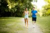 Junge Frau und junger Mann joggen gemeinsam draßen in der Natur.