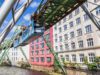 blaue Schwebebahn in Wuppertal vor Häuserfront