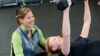 Frau im Fitnessstudio hebt Gewicht unter Anleitung